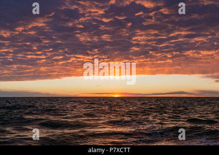 Dramatic sunrise in the ocean. Heavy clouds. Colourful seascape Stock Photo