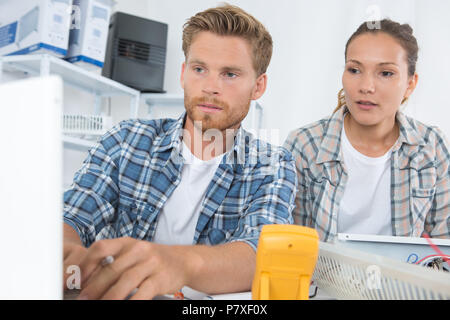 male and female technicians working using multimeter on appliance Stock Photo