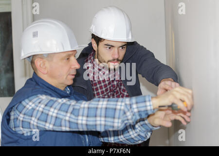 two working builders applies glue on a wall Stock Photo