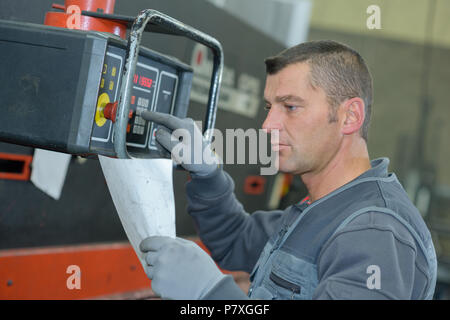 worker entering numbers from instructions into machinery Stock Photo