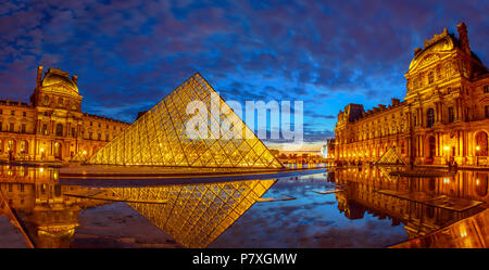 Paris, France - July 1, 2017: panorama of Cour Napoleon of Louvre Museum at blue hour. Glass Pyramid and Pavillon Rishelieu mirroring in a pool at twilight. Louvre Palace is a famous landmark of Paris