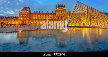 Paris, France - July 1, 2017: panorama of courtyard of Napoleon of Louvre Museum with glass Pyramid and Pavillon Rishelieu at evening. Louvre Palace is a famous landmark of Paris. Night urban scene. Stock Photo