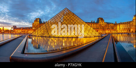 Paris, France - July 1, 2017: panorama of Glass Pyramid and Pavillon Rishelieu reflecting in a pool at twilight. Cour Napoleon at blue hour. Cultural art picture gallery hosting Gioconda of Leonardo.