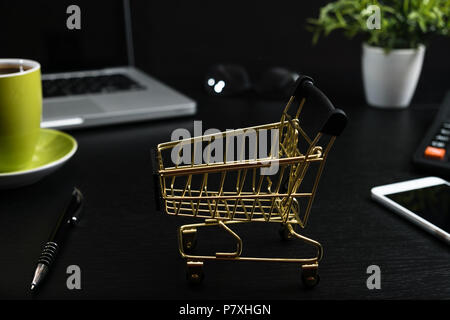 Gold cart, cash and gadgets on a black table. Stock Photo