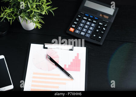 Black desk with computer graph and calculator Stock Photo