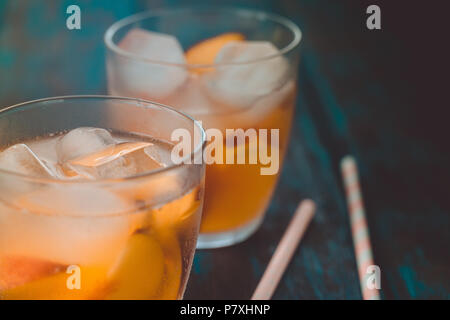 Peach aperol spritz with peach slices on wooden desk. Summer cocktails. Cold peach lemonade. Stock Photo