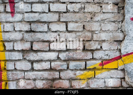 Old painted white brick wall with yellow and red graffiti details. White background Stock Photo