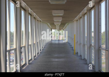 Long indoor enclosed walkway over the interstate 90 expressway full of windows at the CTA Blue Line Train Cumberland Station in Park Ridge, Illinois. Stock Photo