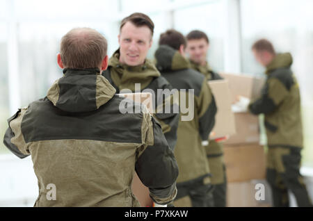 Happy male movers in uniform carrying boxes Stock Photo