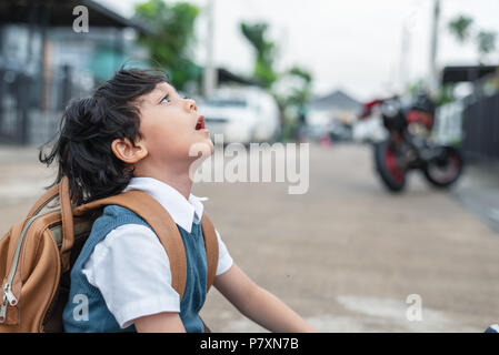 Little boy boring to go to school in the morning. Kids sitting on street. People and Lifestyles concept. Education and Back to school theme. Children  Stock Photo