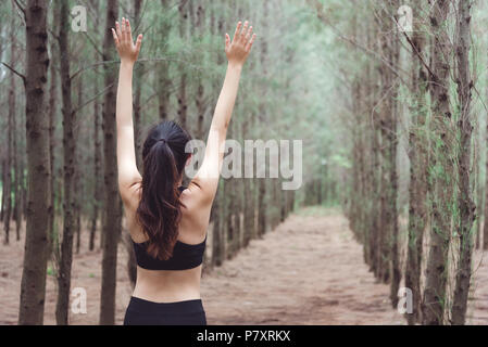 Women breathe fresh air in middle of pinewood forest while exercising. Workouts and Lifestyles concept. Happy life and Healthcare theme. Nature and Ou Stock Photo