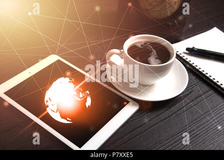 Tablet and black coffee on wooden table with Digital Earth world map and orange light and line dot, Notebook and pen, Technology concept, Drinking and Stock Photo