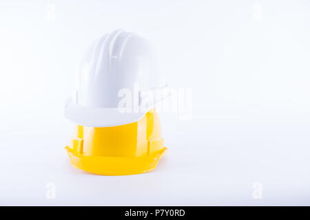 White and yellow safety helmet on white background. Hard hat and thick gloves on white isolated background. Safety equipment concept. Worker and Indus Stock Photo