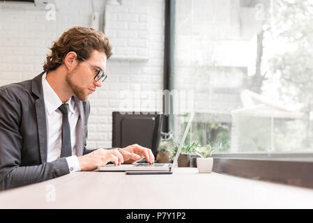 Business man working hard with laptop on desk in office near window. Business and Success concept. People and Occupation concept. Technology and Compu Stock Photo