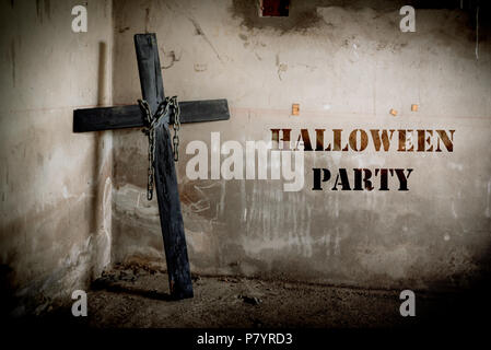 Black cross against the wall with hanging steel chain, Halloween party festival posture advertising. Halloween's Day and ghost concept. Dark and scary Stock Photo