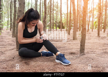 Girl has sport accident injury in forest at outdoors. Healthy and Medicine concept. Adventure and Travel concept. Pine woods theme. Stock Photo