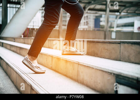 Close up legs of traveling people walking on stepping up stair in modern city. Sneakers and jeans elements. Business and travel concept. City lifestyl Stock Photo