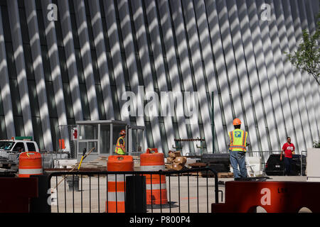 Workers outside the Oculus in New York City put finishing touches on the World Trade Center plaza; orange barriers, shadows against white steel ribs. Stock Photo