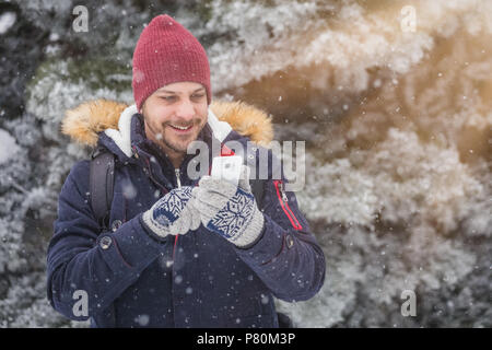 Portrait of young man using smartphone on snowy day. Stock Photo