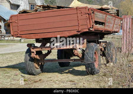 Old red broken tractor trailer cart  located on the village countryside. Sunny spring day outdoor shot Stock Photo