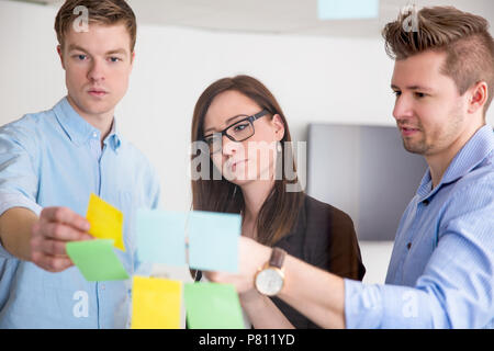 Business Colleagues Discussing Over Adhesive Notes Stuck On Glas Stock Photo