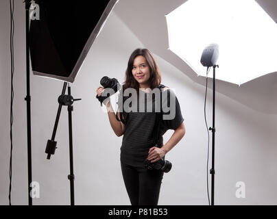Female photographer posing with her cameras in the studio Stock Photo