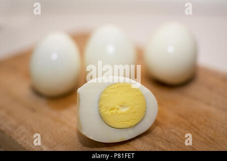 Hard-boiled egg cut in half and in 3 whole eggs background Stock Photo