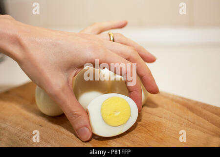 Hard-boiled egg cut in half held between the fingers Stock Photo