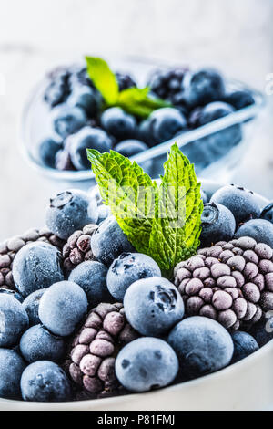 Close-up frozen blueberries and blackberries with mint leaves. Stock Photo