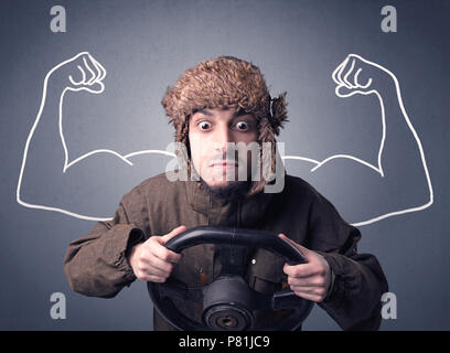 Young man holding black steering wheel with muscly arms drawn next to him Stock Photo