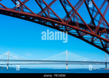 The Queensferry Crossing and the Forth Road Bridge,  seen from a pleasure boat on the Firth of Forth about to sail below the Forth Bridge, summer 2018. Stock Photo