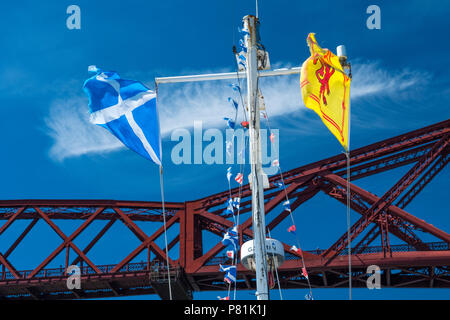 Saltire and Lion Rampant fluttering on a pleasure boat about to sail under the Forth Bridge at Queensferry, Scotland, summer 2018. Stock Photo