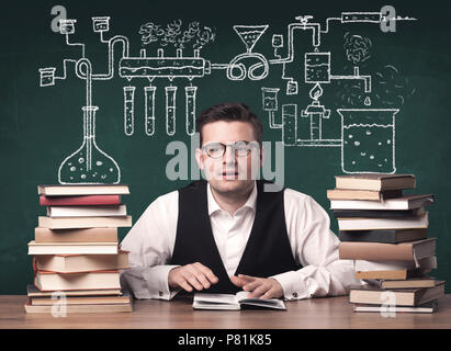 A young chemistry teacher in the middle of a chemical process explanation with tubes, reactions drawn on the blackboard back to school concept. Stock Photo