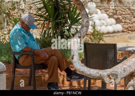 Famagusta, Cyprus - June 29, 2018: Senior man taking an outside nap in the medieval city of Famagusta on a summer morning Stock Photo