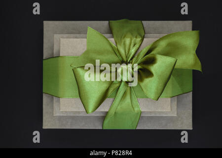 Three brown carton gift boxes bundled with green ribbon isolated on black background and view from above Stock Photo