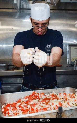 NAVAL BASE KITSAP-BREMERTON, Wash. (May 10, 2016) - Cullinary Specialist Seaman Jared Brenemanpaffumi, a native of St. Augustine, Fla., squeezes lemons over onions and tomatoes to make salsa on board USS Nimitz (CVN 68) in preparation for the upcoming meal. Nimitz is currently undergoing an extended planned incremental maintenance availability at Puget Sound Naval Shipyard and Intermediate Maintenance Facility where the ship is receiving scheduled maintenance and upgrades. Stock Photo