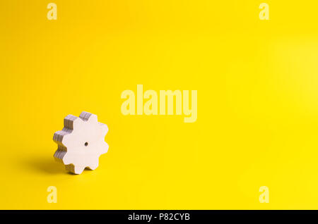 A wooden gear on a yellow background. The concept of technology and business processes. Minimalism. Mechanisms and devices. Work, moving forward. Deve Stock Photo