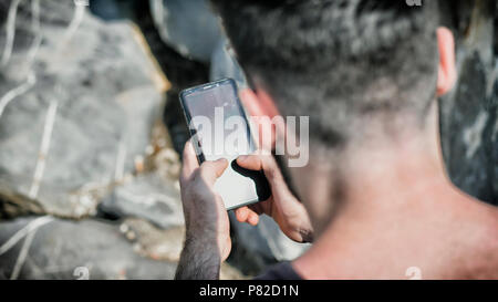 Young man using cell phone to send text message Stock Photo