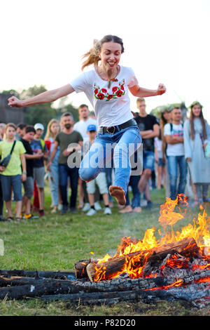 KYIV, UKRAINE - JULY 6, 2018: Young people jump over the flames of bonfire during the traditional Slavic celebration of Ivana Kupala holiday in Pirogo Stock Photo