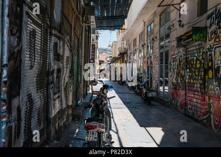 Motorcycles in shadowy tiled street of Athens, Greece. With graffiti on the walls and roller shutters. Stock Photo