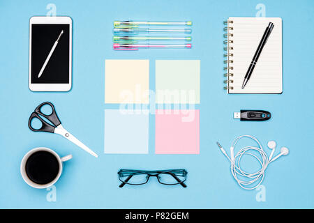 Office desk flat lay. Top view of working space table with morning coffee, smartphone and stationery, office supplies on pastel blue background. Stock Photo