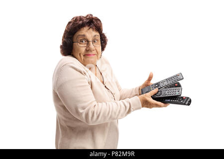 Confused senior lady holding a bunch of remotes isolated on white background Stock Photo