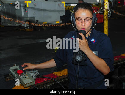 ATLANTIC OCEAN (June 24, 2016) – Machinist’s Mate 2nd Class Itzel Valdez, from San Francisco, communicates using a sound-powered telephone while troubleshooting a conveyor on the aircraft carrier USS George Washington (CVN 73). Washington, homeported in Norfolk, is underway conducting carrier qualifications in the Atlantic Ocean. Stock Photo