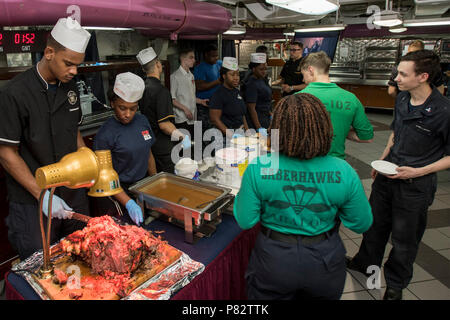 PHILIPPINE SEA (June 26, 2016) Bluejacket and 3&2 Associations’ members serve roast beef, ice cream and cake on the aft mess decks of the U.S. Navy’s only forward-deployed aircraft carrier USS Ronald Reagan (CVN 76). The two volunteer organizations collaborated during a “mess decks take-over” event to show appreciation to the culinary specialists who work in the ship’s galleys every day. The mess decks take-over involved association members volunteering to work in the positions culinary specialists typically fill serving food. The USS Ronald Reagan Carrier Strike Group is on patrol in the U.S. Stock Photo