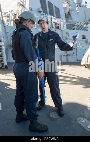 SOUTH CHINA SEA (July 25, 2016) – Fire Controlman 2nd Class Ethan Larsen, right, a member of the anti-terrorism training team, briefs Boatswain’s Mate Seaman Precious Aumua, left, during anti-terrorism force protection drills aboard the Arleigh Burke-class guided-missile destroyer USS Curtis Wilbur (DDG 54). Curtis Wilbur is on patrol with Carrier Strike Group (CSG) 5 in the U.S. 7th Fleet area of responsibility supporting security and stability in the Indo-Asia-Pacific. Stock Photo