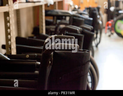 Black wheelchairs with handles lined up in a teaching clinic or ready for use in a hospital Stock Photo