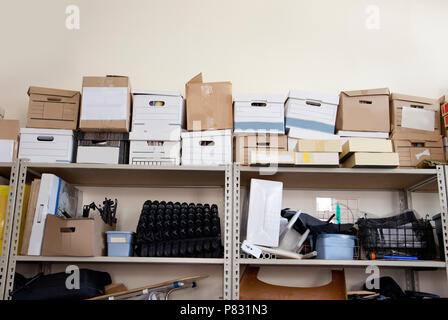 A stack of office supplies piled high in a storage room includes bankers boxes Stock Photo