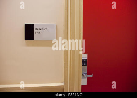 Sign on a red door with a locked keypad says the entrance to a Research Lab. Stock Photo