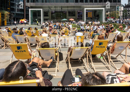 St Helen's Piazza, London. Office workers and tourists spending their lunch break in summer sunshine, chatting, relaxing, eating and drinking Stock Photo