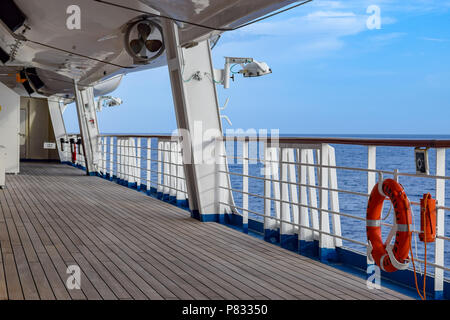 Atlantic Ocean - March 29 2014: Deck onboard Carnival Liberty cruise ship with orange life buoy hanging on side rail. Stock Photo